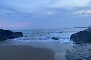 A beach with waves, rocks, and a distant shoreline.