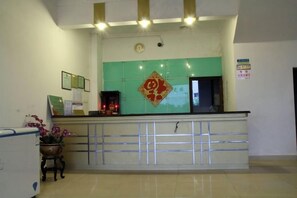 A reception desk with a green and white color scheme, a decorative emblem above it, and a sign on the wall to the right.