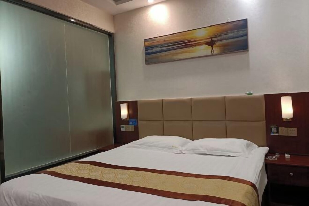 A hotel room with a bed, a painting on the wall, and a nightstand with a phone.