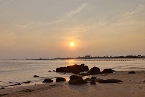 A beach scene with rocks and a distant pier.