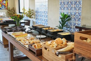 Um buffet com diversos pães e doces.