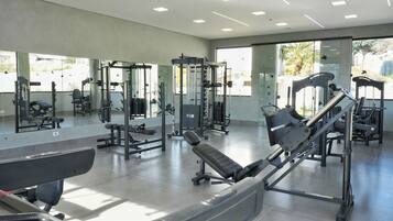 A modern gym with various exercise equipment, large mirrors, and a spacious layout.