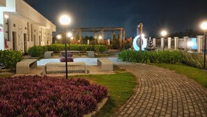 A well-lit outdoor area with a paved walkway, benches, and a water feature. - Bristol Villaggio Rosa Arujá (Arujá)