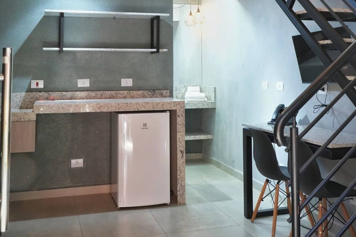 Una cocina moderna con refrigerador empotrado, una encimera y una escalera que conduce a un nivel superior.