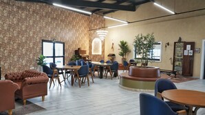 A spacious indoor area with a stone wall, multiple tables and chairs, and a piano. - Bristol Villaggio Rosa Arujá (Arujá)
