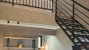 A modern kitchen with a central island, a dining area with chairs, and a staircase leading to an upper level. - Bristol Villaggio Rosa Arujá (Arujá)