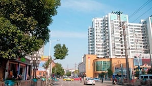 A street with tall buildings, a yellow taxi, and pedestrians. - Xuancheng Zhongzhou Business Hotel (Xuancheng)