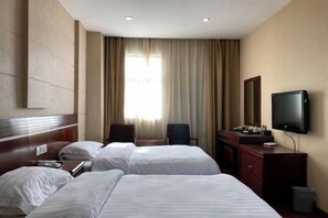 Ein Hotelzimmer mit zwei Betten, einem Fernseher, einem Schreibtisch und einem Stuhl.