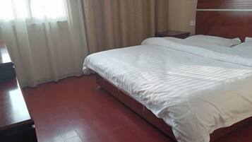 A hotel room with a large bed, wooden headboard, and a nightstand.