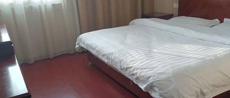A hotel room with a large bed, wooden headboard, and a nightstand.