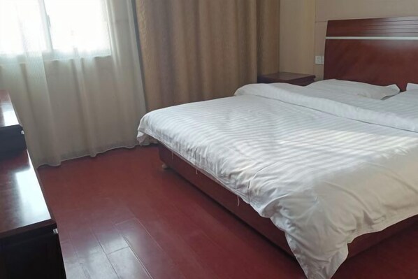 A hotel room with a large bed, wooden headboard, and a nightstand. - Xuancheng Zhongzhou Business Hotel (Xuancheng)