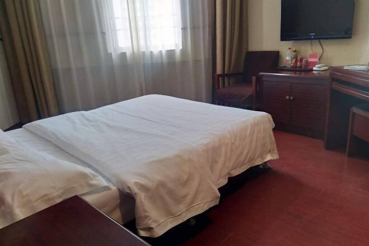 A hotel room with a bed, a desk, a chair, a television, and a cabinet.