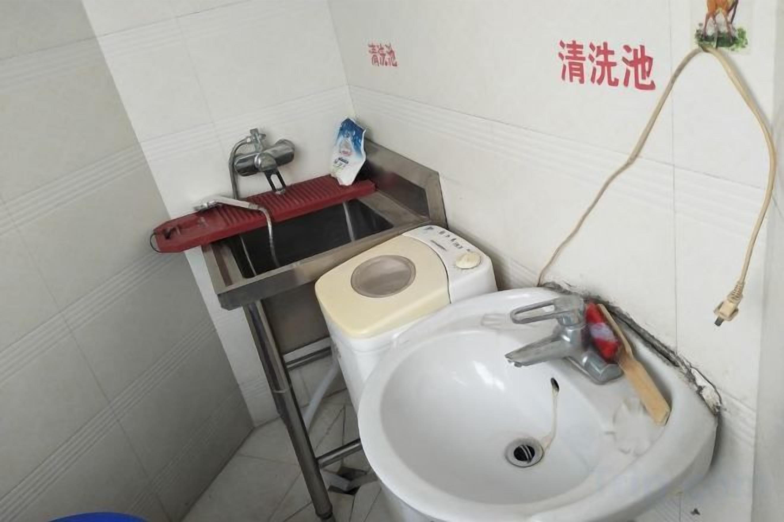 A bathroom with a white sink, a red toothbrush holder, and a white toilet.
