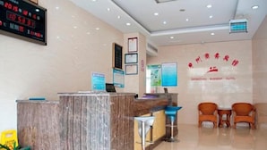 A hotel reception area with a marble counter, two bar stools, and a digital clock displaying the time. - Xuancheng Zhongzhou Business Hotel (Xuancheng)