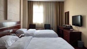 Ein Hotelzimmer mit zwei Betten, einem Fernseher, einem Schreibtisch und einem Stuhl.