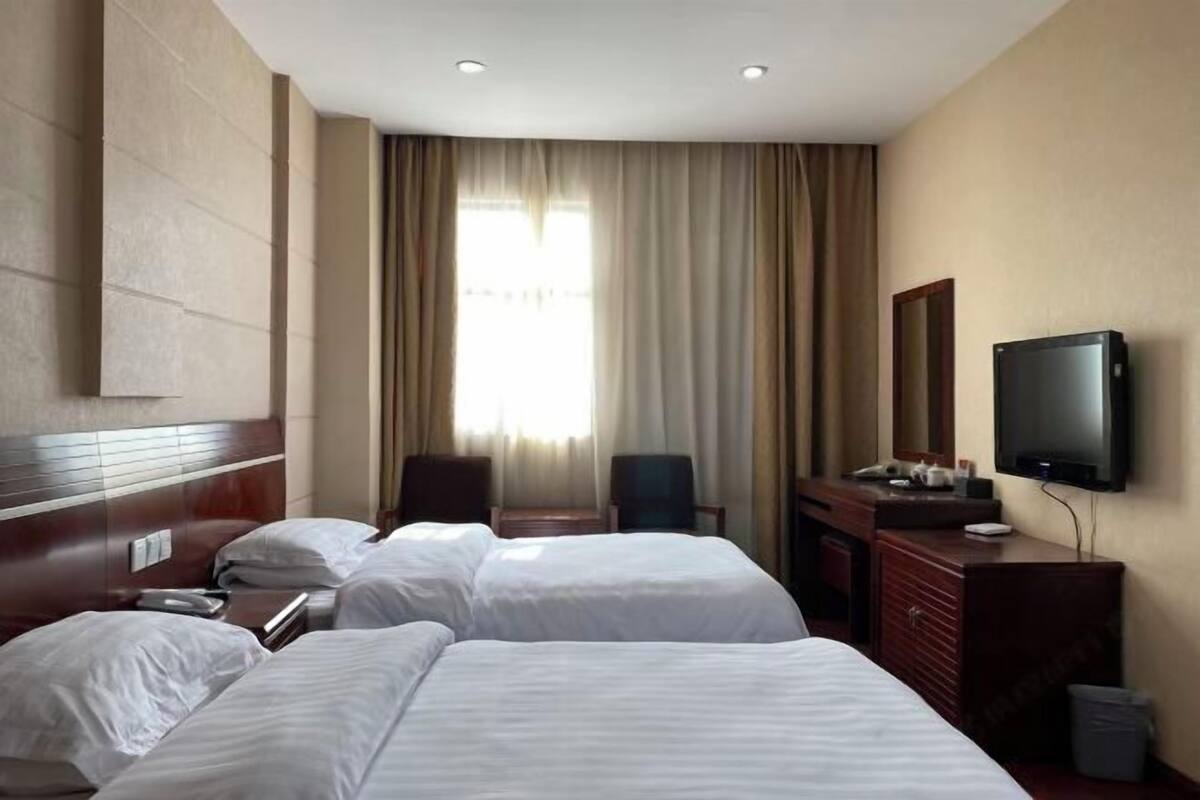 A hotel room with two beds, a TV, a desk, and a chair.
