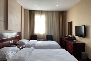 A hotel room with two beds, a TV, a desk, and a chair.