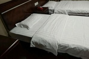 Two beds with white linens, a wooden headboard, and a nightstand with a red object. - Xuancheng Zhongzhou Business Hotel (Xuancheng)