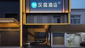 A modern hotel entrance with a prominent sign, a covered walkway, and a clear view into the building.