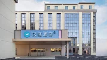 A hotel with a modern facade, a prominent entrance, and a parking lot in front.