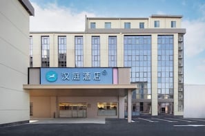 A hotel with a modern facade, a prominent entrance, and a parking lot in front. - HanTing Hotel (Shanghai Hongqiao Railway Station Huqingping Highway) (Shanghai)