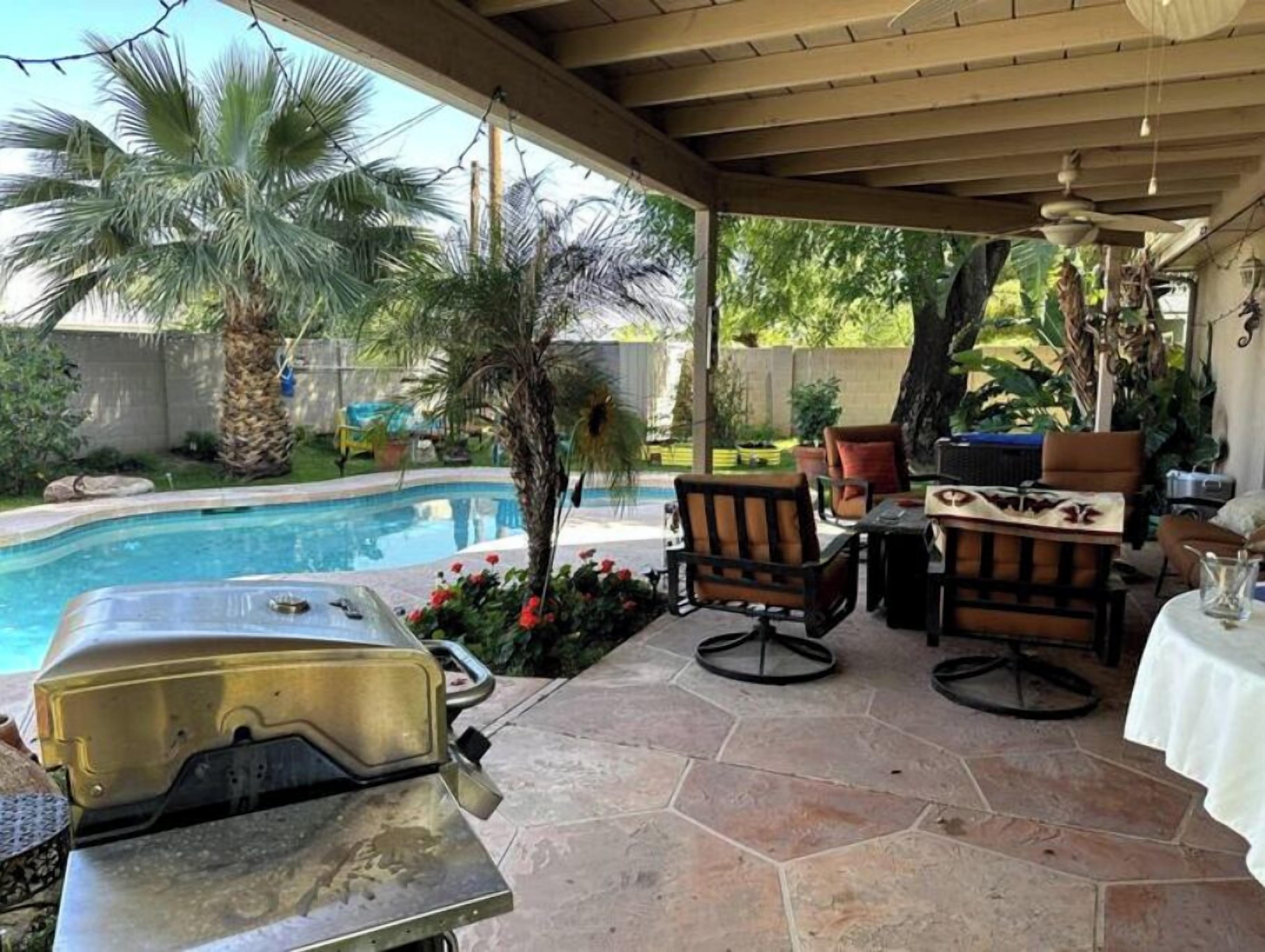 Un patio couvert avec une piscine, du mobilier d’extérieur et un barbecue.