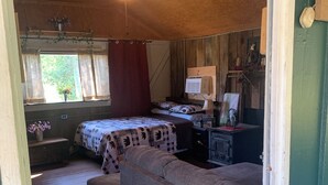 Una habitación acogedora con una cama, un sofá, un escritorio con computadora y un ventilador de techo.