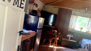 Cocina compacta con refrigerador, comedor con sillas y un sofá en un espacio de estar acogedor.