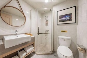 A modern bathroom with a glass-enclosed shower, a sink with a mirror, and a toilet. - New Century Meitu Hotel (Ningbo Tianyi Square, Gulou Metro Station) (Ningbo)
