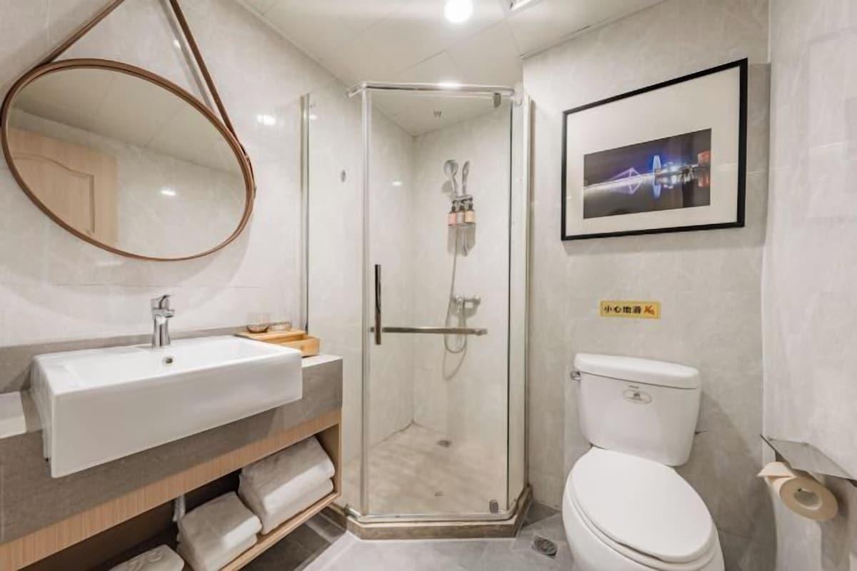 A modern bathroom with a glass-enclosed shower, a white sink, and a toilet.
