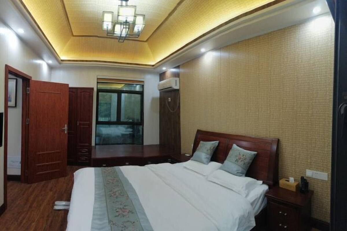 A hotel room with a bed, wooden wardrobe, and a mirror.