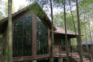 A wooden cabin with large windows, a balcony, and a staircase. - Shikang Shiwai Taoyuan Leisure Tourist Resort (Guangde)
