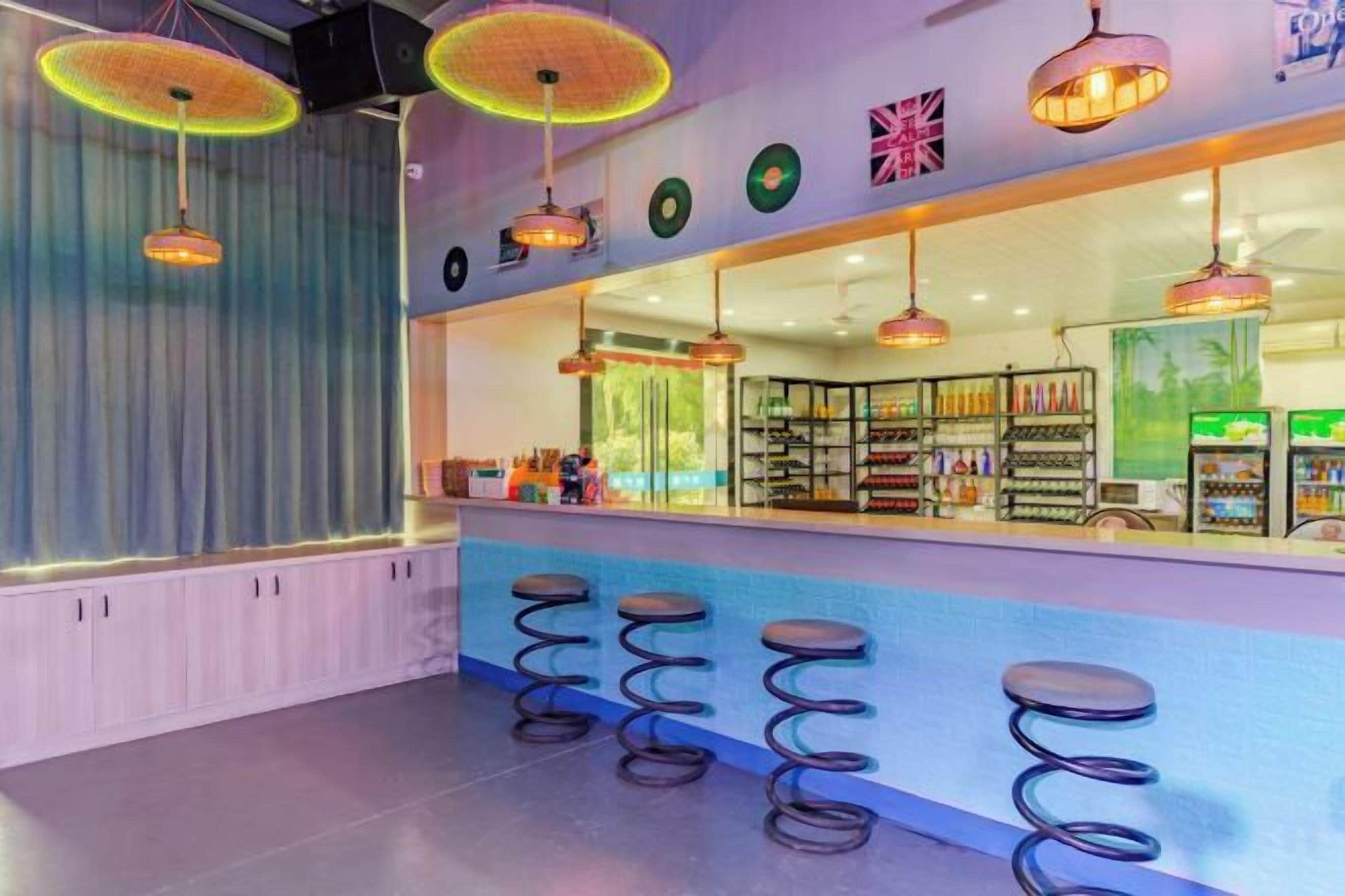Un espace bar avec un comptoir, des tabourets et des étagères remplies de bouteilles.