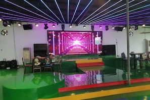 A stage with a neon-lit pathway, a green floor, and a seating area with chairs. - Shikang Shiwai Taoyuan Leisure Tourist Resort (Guangde)