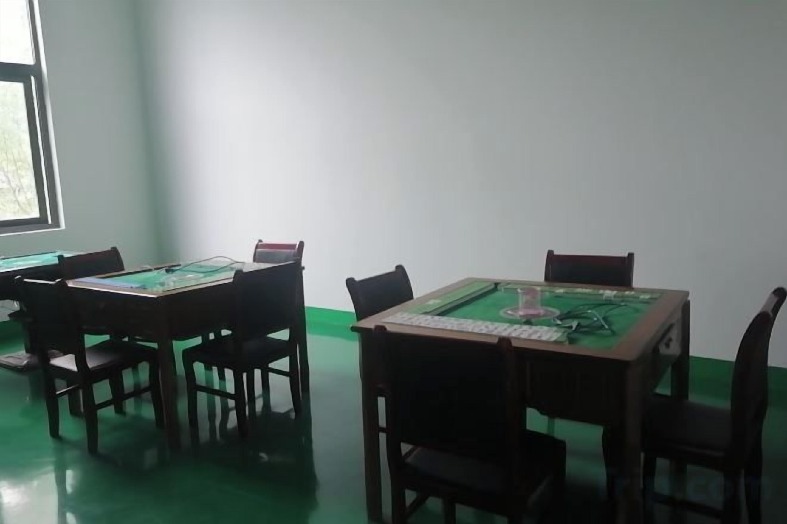 Een kamer met vier houten tafels, elk met een kaarttafel met groene kaarten.