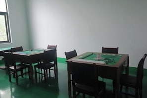 Une pièce comprenant quatre tables en bois, chacune surmontée d’un tapis de jeu vert.