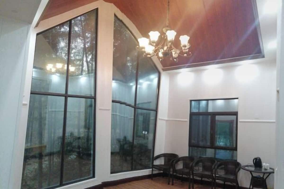 A room with large windows, a chandelier, and a dining area with chairs and a table.