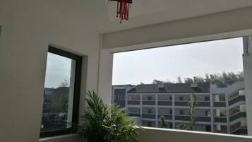 Une pièce dotée d’une grande fenêtre, d’une plante en pot et d’une décoration rouge suspendue.