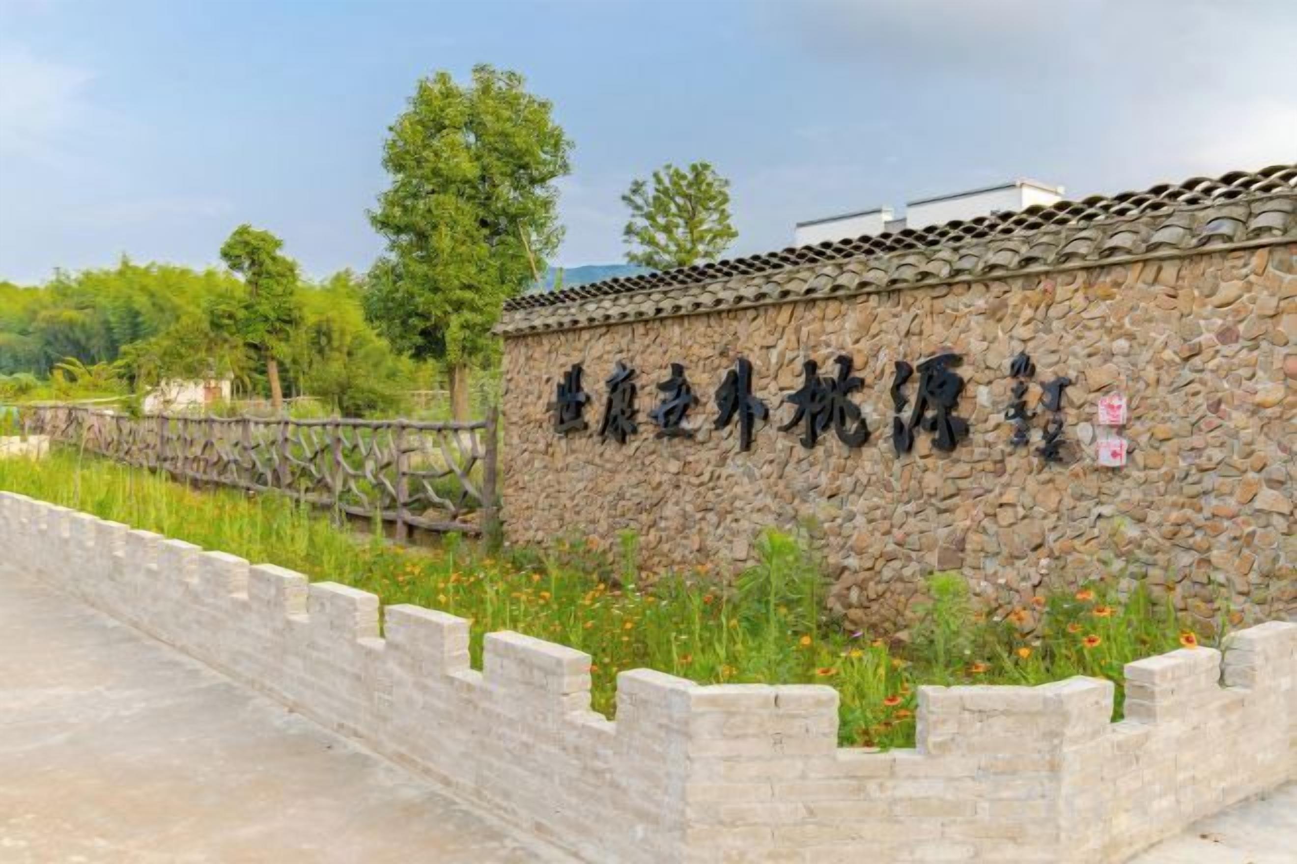 Un mur de pierre orné d’inscriptions, un toit traditionnel recouvert de tuiles et un mur de pierre avec une base en briques.