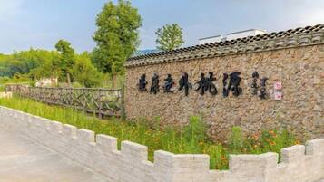 Un mur de pierre orné d’inscriptions, un toit traditionnel recouvert de tuiles et un mur de pierre avec une base en briques.