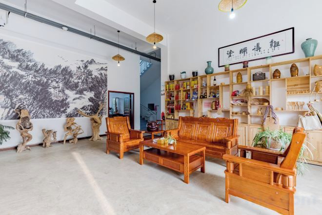 A spacious room with a large window, wooden furniture, and a bookshelf filled with various items.
