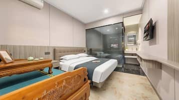 Habitación de hotel con una cama, un banco de madera, una mesita con un marco de fotos y un espejo en la pared.