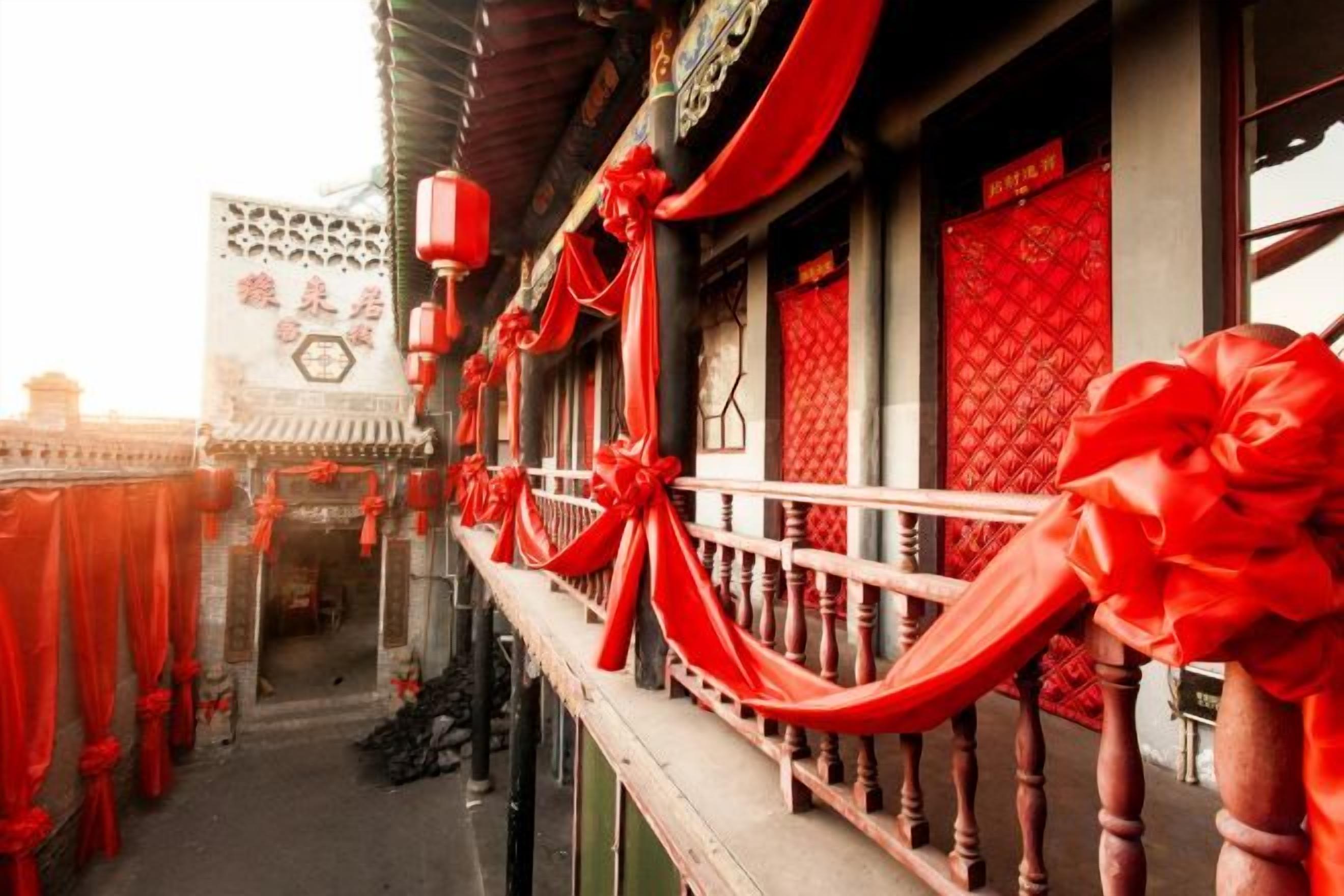 A traditional building with a balcony, red decorations, and a sign with Chinese characters.