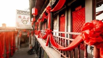 A traditional building with a balcony, red decorations, and a sign with Chinese characters.