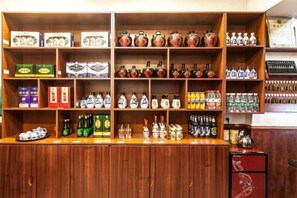 A bar area with shelves stocked with various bottles and boxes, a wooden counter, and a red cabinet. - Yuanlaiju Inn (Pingyao County)