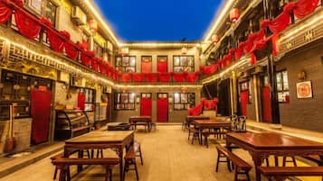 Un patio con mesas y sillas, arquitectura tradicional y decoraciones rojas.