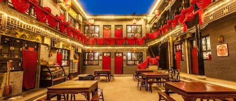 A courtyard with tables and chairs, traditional architecture, and red decorations.