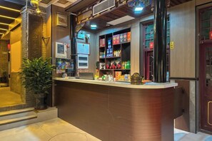 A reception area with a counter, shelves with various items, a potted plant, and a door with a handle. - Yuanlaiju Inn (Pingyao County)
