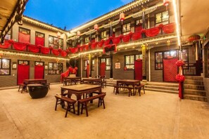 A courtyard with tables and chairs, a building with red decorations, and a staircase. - Yuanlaiju Inn (Pingyao County)