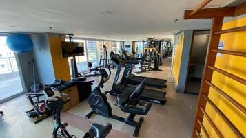 Uma academia com esteiras, bicicletas ergométricas e aparelhos de musculação.